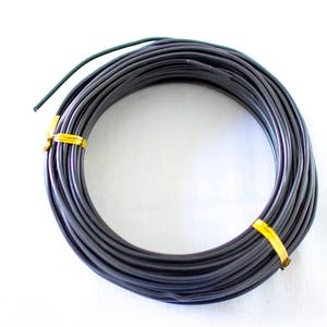May include: A coil of black wire wrapped with a yellow band. The wire is coiled in a circle and is ready to be used for crafting or other projects.