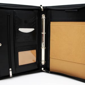 May include: Black leather zippered binder with a ring mechanism and a tan interior. The binder has multiple pockets and slots for holding documents and cards.