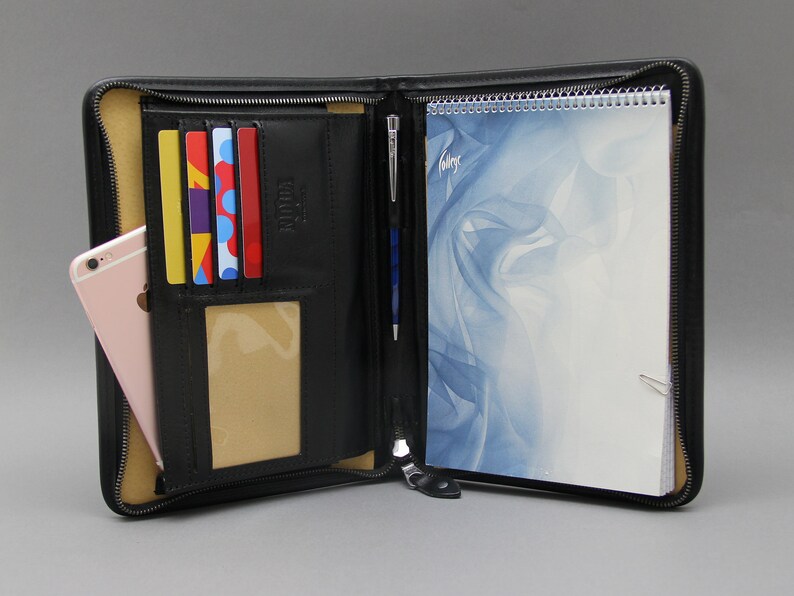 May include: Black leather zippered portfolio with a notepad, pen, and card slots. The notepad has a blue and white abstract design.