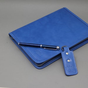 May include: A blue leather zippered portfolio with a pen and a key chain with a blue leather tag. The tag has the word "MODIK" embossed on it.