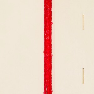 Op de afbeelding: Een rood, glinsterend, plastic, snoepstokvormig ornament met een lang, dun, verticaal gedeelte en drie kortere, horizontale gedeelten.