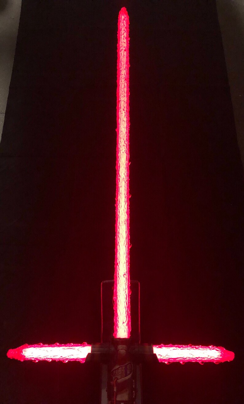 Op de afbeelding: Een rood lichtzwaard met een getextureerd blad en een zwarte handgreep. Het lichtzwaard is aan en het blad gloeit.