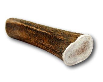 May include: A brown antler dog chew with a white, smooth end. The antler is a natural dog chew.
