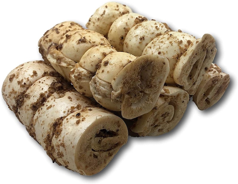 May include: A close-up of several dog chew treats. The treats are made of rolled-up pig ears with a brown, crunchy coating.