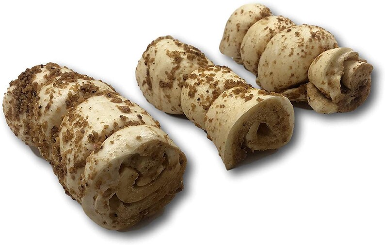 May include: Three dog chew toys made of rolled up, light brown, textured material. The chew toys are covered in brown crumbs.