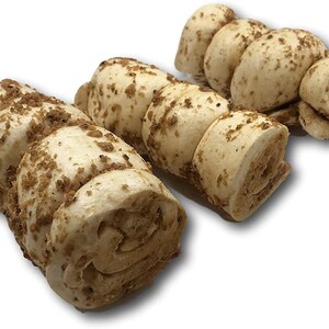 May include: Three dog chew toys made of rolled up dough with a crunchy coating. The chew toys are light brown in colour and are shaped like a spiral.