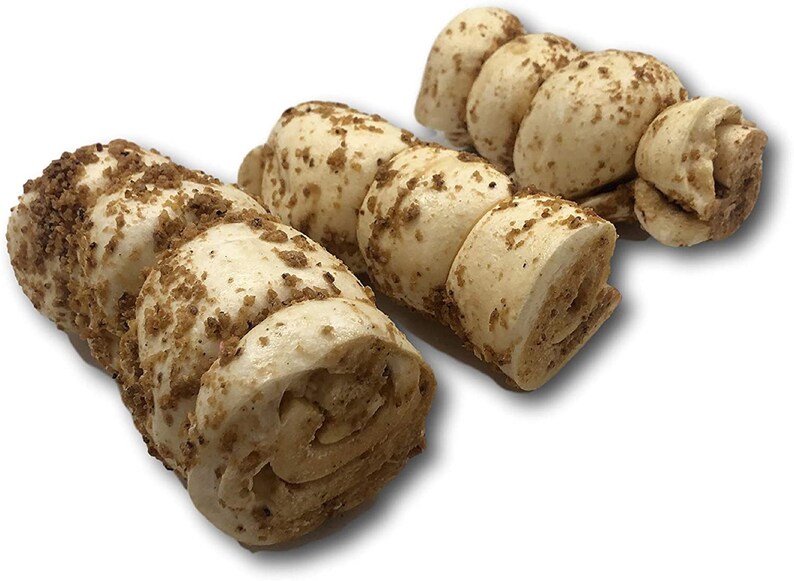 May include: Three dog chew toys made of rolled up dough with a crunchy coating. The chew toys are light brown in colour and are shaped like a spiral.