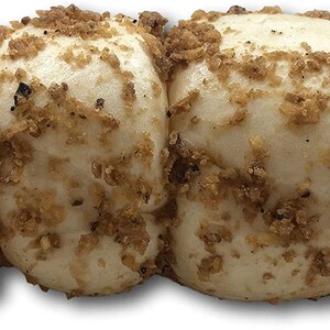 May include: A close-up of four white buns covered in a brown, crumbly topping. The buns are arranged in a row and appear to be soft and fluffy.