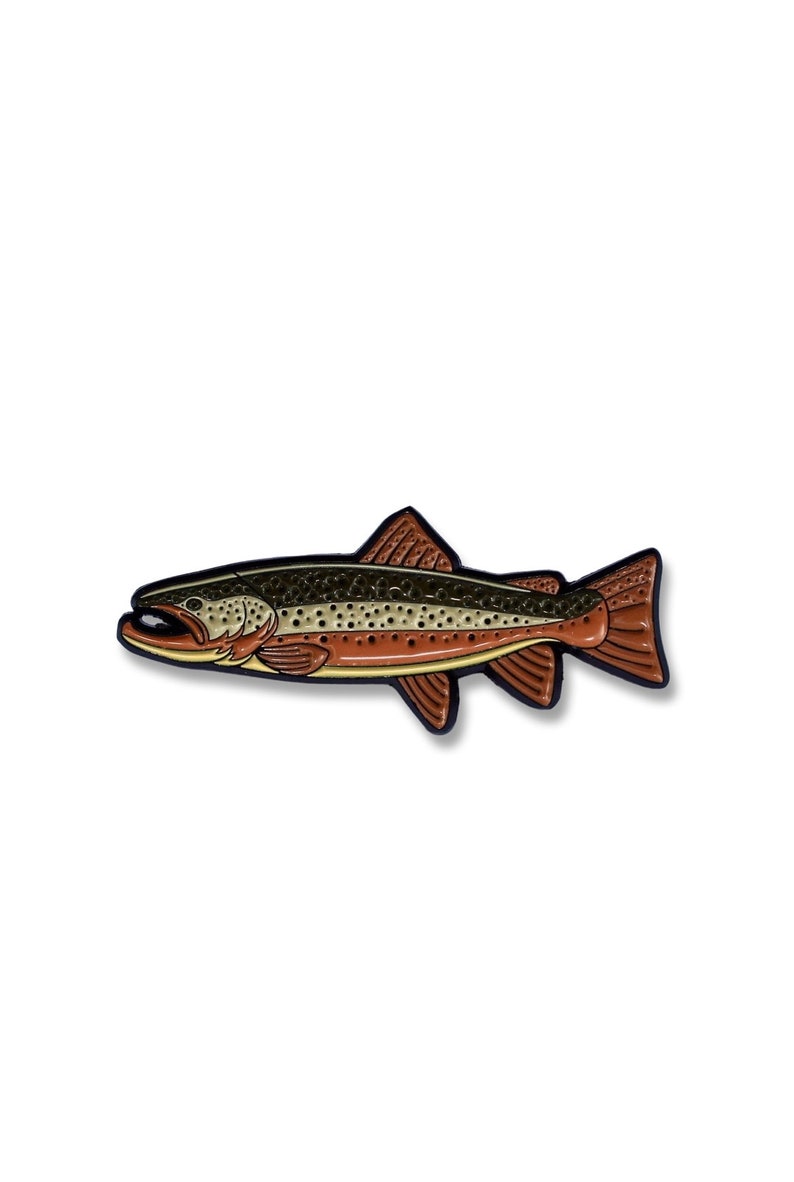K&ouml;nnte beinhalten: Eine Emaille-Anstecknadel mit einem braunen und gr&uuml;nen Fisch, der eine Forelle darstellt, mit schwarzen Umrissen.