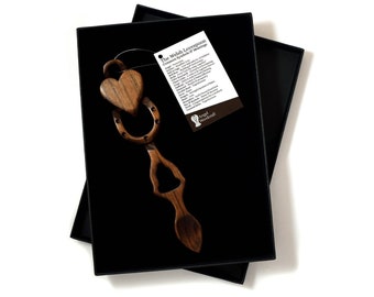May include: A wooden heart-shaped love spoon in a black box with a white tag that reads "The Welsh Lovespoon: Customs, Rituals & Meaning".