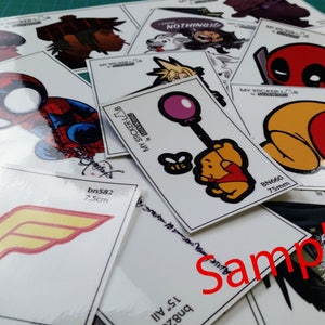 May include: Assortment of colorful stickers featuring various cartoon characters, including Winnie the Pooh, Spiderman, Deadpool, and Wonder Woman. The stickers are printed on white glossy paper and have a variety of sizes. The text "MY STICKER-LAB" and "NOTHING" are visible on some of the stickers.