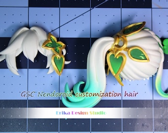May include: Customizable hair pieces for a Nendoroid doll. The hair is white with green and gold accents. The text "GSC Nendoroid customization hair" and "Erika Design Studio" is visible in the image.