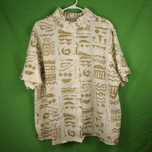 Puede incluir: Camisa blanca de manga corta con botones y estampado geométrico marrón. La camisa tiene cuello y cierre de botones.