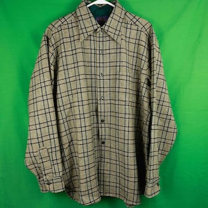May include: A long-sleeved plaid shirt in brown, black, and white. The shirt has a button-down collar and a button front.