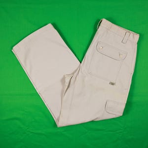 May include: Beige cargo pants with multiple pockets, including two button-flap pockets on the back and a cargo pocket on the leg. The pants are made of a durable fabric and feature a classic design.