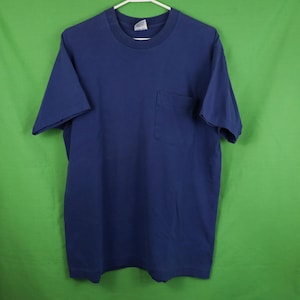 Könnte beinhalten: Ein einfarbiges, marineblaues T-Shirt mit einer einzigen Tasche auf der linken Seite.