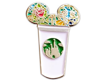 Può includere: Una tazza di caffè bianca con un logo verde di un castello. La tazza ha due orecchie di Topolino in cima, una con una rosa in vetro colorato e l'altra con un'immagine in vetro colorato di Belle de La Bella e la Bestia.