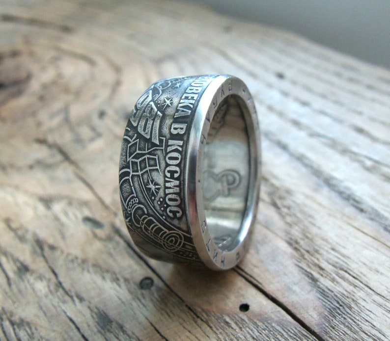 Op de afbeelding: Een zilveren ring gemaakt van een munt met de inscriptie "ПОЛЕТ ЧЕЛОВЕКА В КОСМОС" (Vlucht van de mens naar de ruimte) en een afbeelding van een raket.