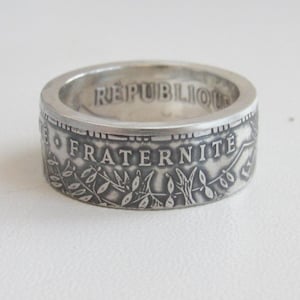 Puede incluir: Anillo de plata hecho con una moneda francesa con la inscripción "REPUBLIQUE FRANCAISE" y "FRATERNITE" en la banda.