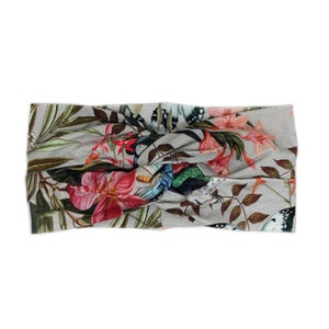 Puede incluir: Diadema gris con estampado floral y de mariposas. El dise&ntilde;o presenta flores rosas y rojas, hojas verdes y mariposas en tonos azules, blancos y negros. La diadema est&aacute; hecha de una tela suave y el&aacute;stica.