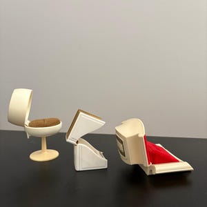May include: Miniature ivory-colored chair with a brown seat and a small, open ivory jewelry box with a red velvet interior. Another ivory jewelry box is open, revealing a gold-colored interior.