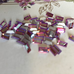 Peut inclure: Un tas de petits strass rectangulaires violets irisés.