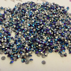 Puede incluir: Un montón grande de piedras de cristal azul iridiscente y plateadas. Las piedras de cristal son pequeñas y tienen una parte posterior puntiaguda.