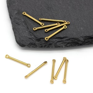 Peut inclure: Un groupe de connecteurs métalliques de couleur dorée avec des boucles à chaque extrémité. Les pièces sont disposées sur une surface en ardoise noire.