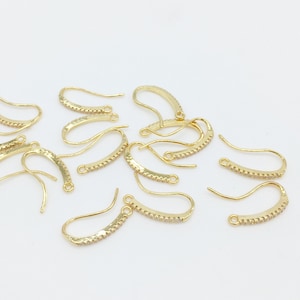May include: A group of gold-toned earring hooks with a row of small clear rhinestones on each hook.