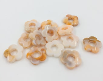 May include: A group of white and orange flower-shaped beads with a hole in the center. The beads are made of a marbled material and have a slightly iridescent finish.
