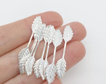 May include: A set of eight silver arrow charms with leaf-shaped tips. The charms are arranged in a fan shape, with the tips of the leaves pointing outwards.