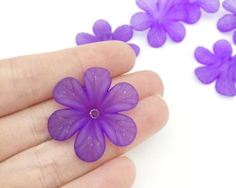 May include: Purple plastic flower beads with a hole in the centre for stringing. The beads are translucent and have a slightly textured surface.