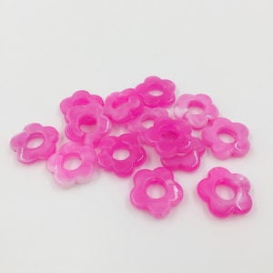 May include: A group of pink and white flower-shaped plastic beads with a hole in the centre.
