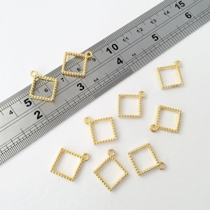 May include: Eight gold-toned metal square-shaped pendant charms with a beaded border. The charms are approximately 2.5 cm in size and have a loop at the top for attaching to jewellery.