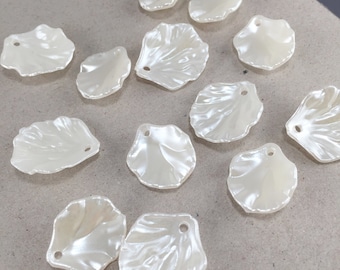 Puede incluir: Un conjunto de cuentas en forma de pétalo, de color blanco roto y con acabado nacarado. Cada cuenta tiene un agujero para ensartar. Perfectas para bisutería o proyectos de manualidades.