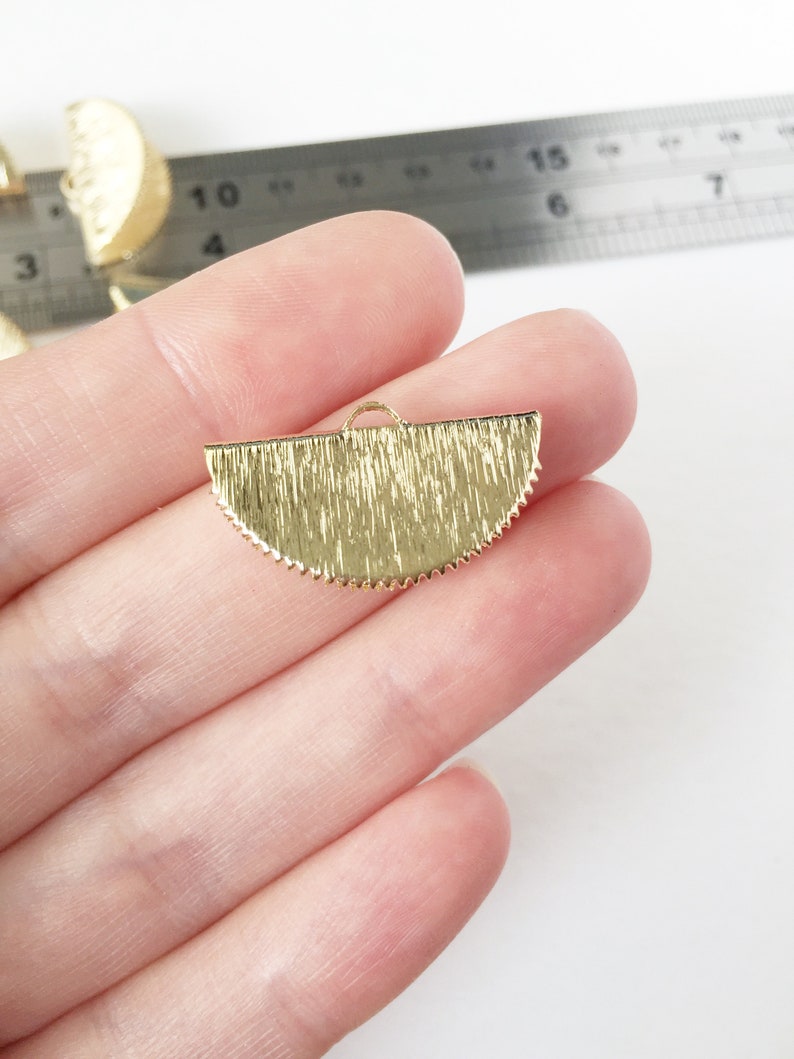 May include: Gold-toned metal half-circle pendant with a textured surface and a small loop at the top.
