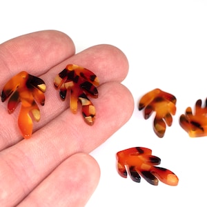 May include: Five brown, orange and black tortoiseshell leaf-shaped resin embellishments.