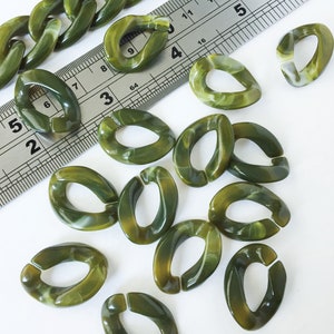 May include: A collection of green and white marbled oval-shaped plastic chain links. The links are approximately 1 inch in length and have a smooth, glossy finish.