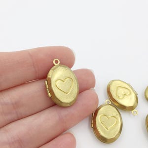 May include: Five gold oval-shaped locket pendants with a heart design on the front. The lockets have a hinged opening.
