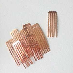 May include: A set of 11 rose gold hair combs. The combs are small and have a wavy design. They are perfect for adding a touch of elegance to any hairstyle.
