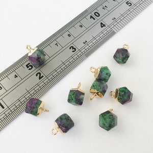 May include: Seven green and purple gemstone pendants with gold jump rings. The gemstones are approximately 1 cm in size.