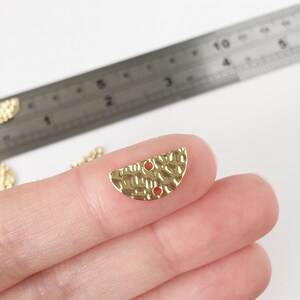 May include: Two gold-toned half-circle metal embellishments with a hammered texture and two holes. The embellishments are approximately 2.5 cm in diameter.