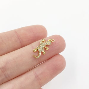 May include: Gold-toned charm featuring a detailed gecko design with clear crystal accents.