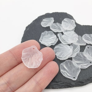 May include: A pile of clear plastic flower petals with a hole at the top for stringing. The petals are translucent and have a slightly textured surface.