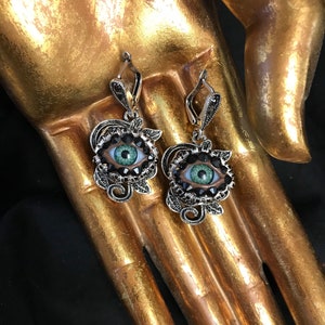 Pendientes de plata envejecida con diseño de rosa y ojos, adornados con lirios verdes naturales y diamantes de imitación colocados a mano.