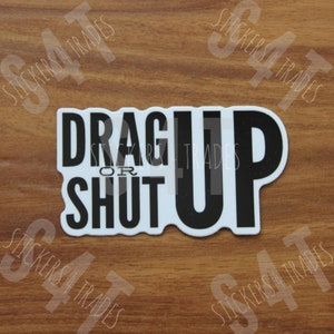 May include: White sticker with black text that reads "Drag Up or Shut Up".