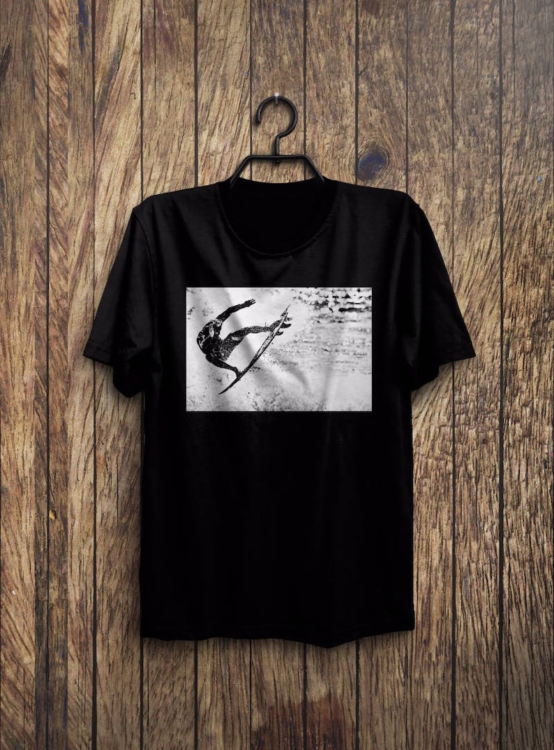 May include: Black t-shirt with a graphic print of a person surfing a wave. The graphic is in black and white.