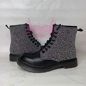 Może przedstawiać: Czarne skórzane botki ze sznurowaniem i grubą podeszwą. Botki są pokryte tęczowymi kryształkami.