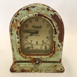 May include: A vintage green and brown metal timer with the words "Monarch Jewelled Movement" and "Automatic" and "Non Automatic" on the face. The timer has a large round clock face with black numbers and hands.