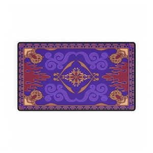 May include: A rectangular mat with a purple background and a decorative design. The design includes swirling patterns, a central floral motif, and stylized tiger heads. The border is a dark purple with a repeating pattern.